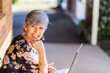 © Austockphoto - Portrait of a happy smiling middle aged woman working on her laptop outside