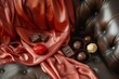 luxurious silk scarf laid out with gourmet chocolates on leather armchair cushion