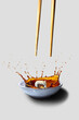 Sushi falling from chopsticks into a bowl of soya sauce