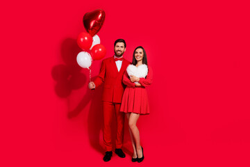 Poster - Full body portrait of two classy nice people hold balloons heart figure soft pillow empty space isolated on red color background