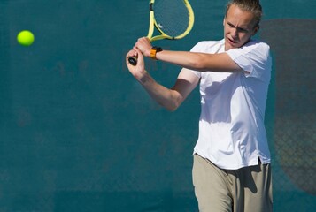 Wall Mural - Tennis player playing tennis on a hard court on a bright sunny day	