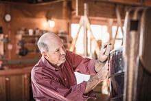 Senior Man Building And Working On A Wooden Boat In A Workshop. Port Townsend, Washington, USA