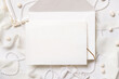 Blank card near white decorations, pebbles and silk ribbons top view, wedding menu mockup