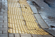 Rough cracked yellow cement braille brick. Broken yellow tactile tiles for blind peoples. Damaged warning tiles on sidewalk. Damaged tactile paving on pavement. Selective focus