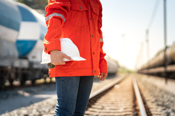 Wall Mural - Close-up at a worker is holding white safety helmet, posing on crude oil tanker freight train as blurred background. Safety working in the challenge industrial concept scene.
