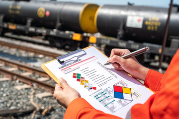 Wall Mural - action of an engineer is checking on chemical hazardous material checklist form with background of t