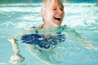 © MACO - Older woman swimming in an indoor pool and doing water gymnastics.