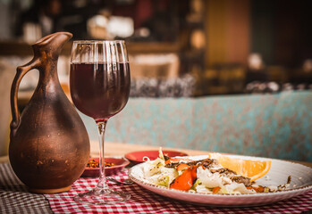 Wall Mural - Greek salad and glass of red wine on the oak table