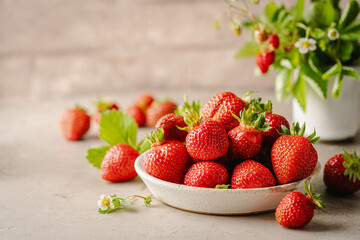 Wall Mural - Heap of fresh ripe strawberries in ceramic bowl on rustic light background.