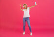 Leinwandbild Motiv Cheerful blonde lady wearing headphones making selfie on smartphone, studio