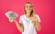 Leinwandbild Motiv Happy Young Blonde Woman Holding Money Cash Against Pink Backdrop