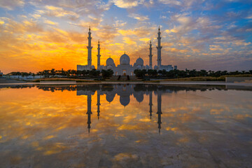 the sheikh zayed grand mosque, the largest mosque in the uae at sunset, and reflected in the oasis o