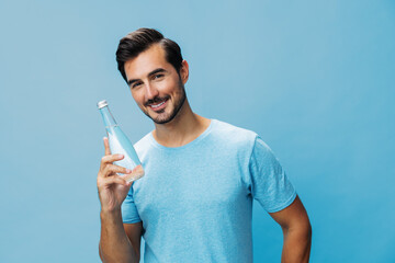 Wall Mural - Attractive man smile lifestyle water studio portrait blue t-shirt bottle happy healthy sport drink