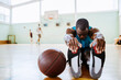 © Marko Geber - Young man stretching before playing basketball in an indoor basketball gym