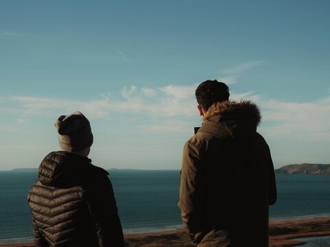 Two persons view the north landscape with the sea and the cliff in the background.