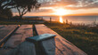 Ein Smartphone liegt auf einem Holztisch auf einer Wiese am See bei Sonnenuntergang oder Sonnenaufgang und ist eine entspannte Szene