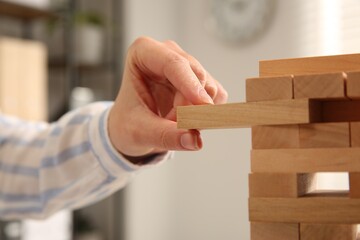 Wall Mural - Playing Jenga. Woman removing wooden block from tower indoors, closeup