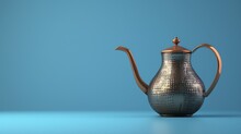  A Silver Teapot With A Copper Lid On A Blue Background With A Reflection Of The Teapot On The Ground And The Top Of The Teapot With A Copper Lid.