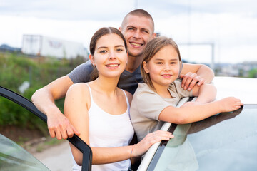 Happy family posing near new car outdoor