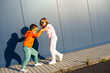 Eight-year-old boy and girl pushing each other on the street against the background of a blue wall