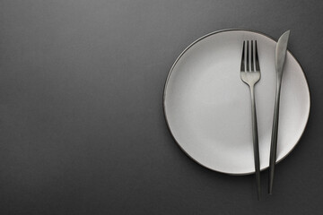 Sticker - Clean plate, fork and knife on grey table, top view. Space for text