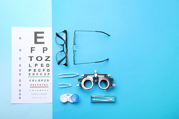 Poster - Flat lay composition with vision test chart and glasses on light blue background, space for text