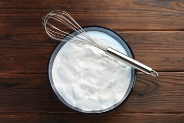 Wall Mural - Bowl with whipped cream and whisk on wooden table, top view