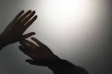 Silhouette of ghost behind glass against light grey background, closeup. Space for text