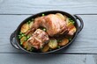 Tasty cooked rabbit with vegetables in baking dish on grey wooden table, top view