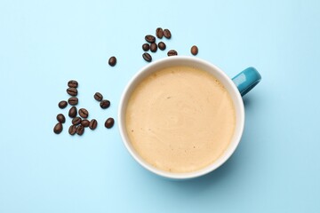 Sticker - Fresh coffee in cup and roasted beans on light blue background, top view