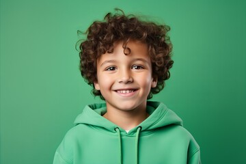 Portrait of a cute little boy with curly hair on a green background