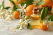 A small amber glass bottle with neroli essential oil surrounded by delicate white orange blossoms on a textured surface.