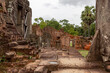 Stone brick temple ruin building complex walls and lush green rain forest in Angkor Wat historical site Siem Reap Cambodia on a cloudy sky day