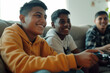 hispanic black kids playing video game with controller smiling teens friends friendship happy complicity bond on a sofa in a living room having fun wearing yellow hoodie cheerful upbeat boys
