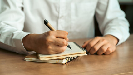 Wall Mural - businessman working at work table,home office desk background, checklist writing planning investigate enthusiastic concept. Male hand taking notes on the notepad.