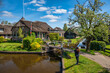 © Noppasinw - Giethoorn Netherlands, city skyline at canal and traditional house in Giethoorn village with tourist woman