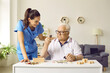 © Studio Romantic - Friendly young woman nurse or social worker helping an elderly man sitting at the table to solve jigsaw puzzles game in nursing home. Concept of memory training for dementia prevention.