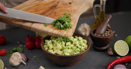 Wall Mural - Salsa recipe - Woman cutting and chopping cilantro or parsley greens on a wooden cutting board at domestic kitchen