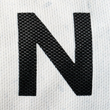 Black letter N on white painted fabric material. English alphabet.