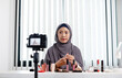 © Orathai - Muslim women making video beauty vlogger bloggers doing a cosmetic makeup tutorial vlog with brushes looking camera Save clips and share them on social media live via the internet Online