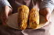 Caucasian male hands holds plate with grilled sweetcorn