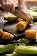 Female hands cut sweetcorn cobs on cutting board low angle view