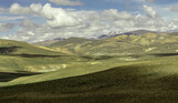 Fototapeta  - Spectacular landscape in the Peruvian Altiplano in the Andes Mountains between Cabanaconde and Arequipa, Peru. Green hills, snowy peak.Blue sky, white clouds.