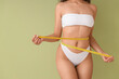 Beautiful young African-American woman with stretch marks on her body and measuring tape against green background, closeup