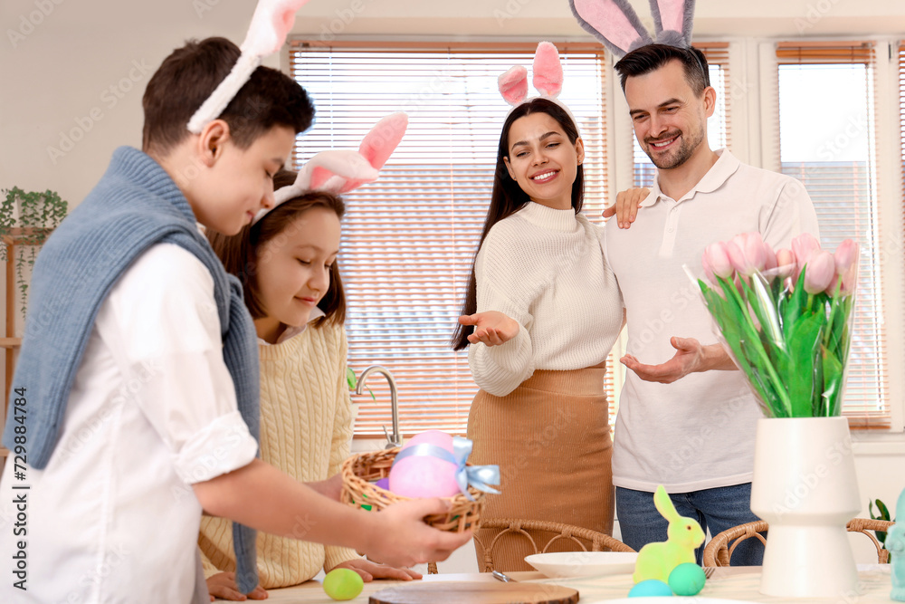 Happy parents with their little children in dining room on Easter Day