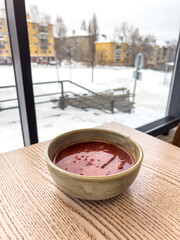 Wall Mural - Red borscht on a wooden table in winter