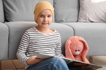 Sticker - Little girl after chemotherapy with book and toy at home. International Childhood Cancer Day