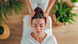 une femme allongée sur le dos sur une table de massage se fait masser la tête par une masseuse professionnelle