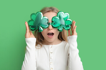 Canvas Print - Cute little girl in decorative glasses in shape of clover on green background. St. Patrick's Day celebration