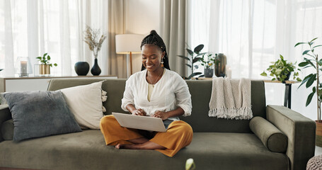 Wall Mural - Black woman on sofa, smile and typing on laptop for remote work, social media or blog post research in home. Happy girl on couch with computer checking email, website or online chat in living room.